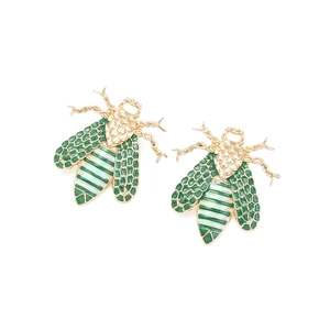 Macro view of gold bee earrings featuring green enamel wings and honeycomb texture