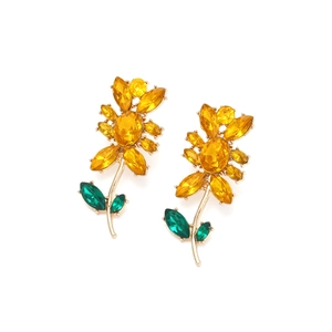 Nahaufnahme von Sonnenblumen-Ohrringen mit gelben Kristallen und grünen Kristallblättern