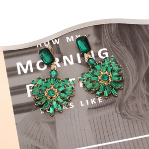Close-up of luxury emerald green rhinestone heart earrings with radiant sunburst design