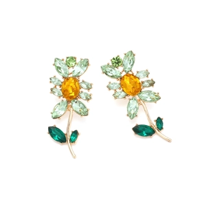 Makroaufnahme der Sonnenblumen-Ohrstecker mit gelben Kristallen und grünen Edelsteinen