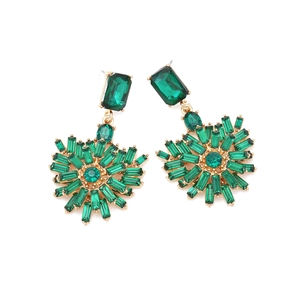 Detailed shot of emerald green crystal drop earrings with vintage gold settings