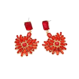 Close-up of golden earrings featuring radial heart-shaped red baguette crystals