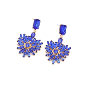 Detail of gold-tone earrings featuring dark blue crystals in a radiant sunflower pattern