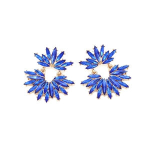 Detailed close-up of golden fan-shaped earrings with blue crystals and claw setting