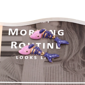 Detail of pink marble resin and purple enamel fish bone earrings on magazine