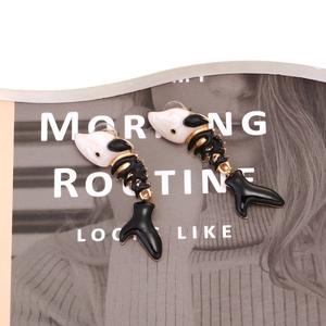Detail of fish bone drop earrings with black and white enamel on a fashion magazine