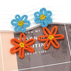 Detail of handmade crocheted blue and orange floral earrings with yellow bead centers