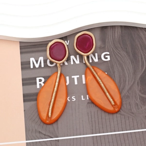 Detail of geometric resin earrings with orange and pink leaf accents and gold wire wrapping
