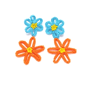 Detail of handmade crochet flower earrings featuring blue and orange petals with yellow beads