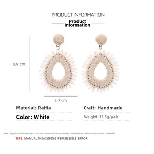 Detail of white raffia drop earrings with 8.9cm x 5.7cm dimensions and handmade texture
