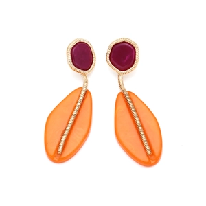 Close-up of geometric resin earrings with fuchsia studs and orange leaf pendants