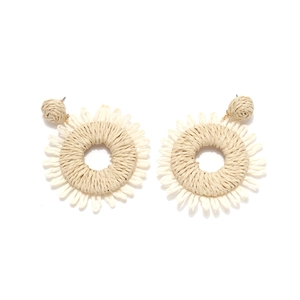 Detailed macro view of beige raffia hand-woven round sunflower bohemian earrings