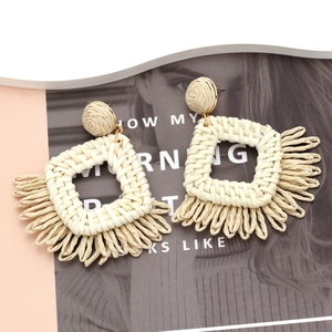 Bohemian raffia tassel earrings with geometric woven square design on a summer background
