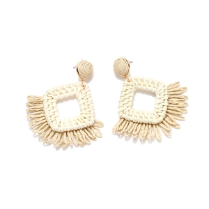 Detail of bohemian raffia tassel earrings featuring a geometric square woven design