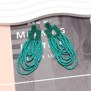 Detail of green handmade bohemian beaded tassel earrings with floral stud and curved chains