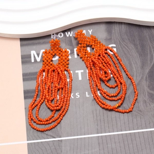 Detailed close-up of orange handmade bohemian beaded tassel earrings with floral stud top