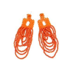Detailed view of handmade bohemian orange multi-layer beaded tassel earrings on white backdrop