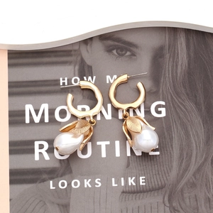 Retro gold metal flower earrings with imitation pearl drops on a fashion magazine