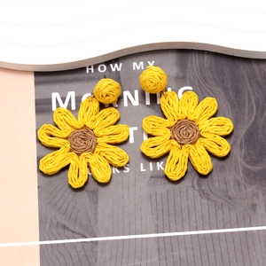 Macro detail of handmade woven sunflower earrings with vibrant yellow raffia petals