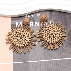 Detailed view of bohemian woven raffia sunflower earrings with beaded centers