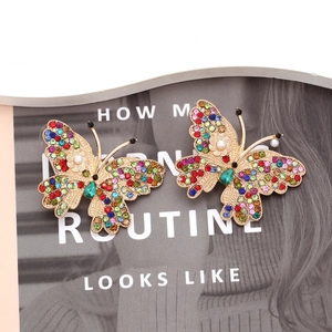Macro detail of butterfly earring with colorful rhinestones and white faux pearl accent