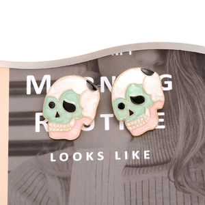 Detail of skull stud earrings with colorful enamel finish and golden beaded edges