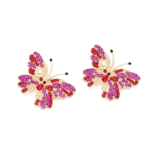 Close-up of golden butterfly earrings with colorful rhinestones and faux pearls