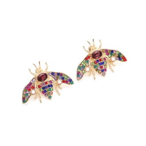 Vue macro de boucles d'oreilles abeilles avec strass colorés et perles sur métal doré