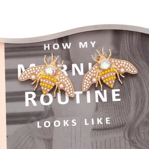 Détail macro de boucles d'oreilles abeille avec perles et strass sur magazine