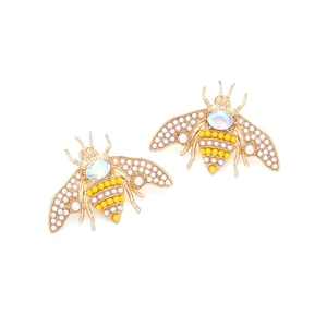 Vue macro de boucles d'oreilles abeilles avec perles et strass aux reflets irisés