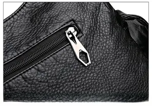 Macro detail of the silver hardware zipper puller on the black lychee pattern leather bag