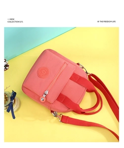 Macro view of coral pink nylon crossbody bag with zipper pocket and rubber logo detail