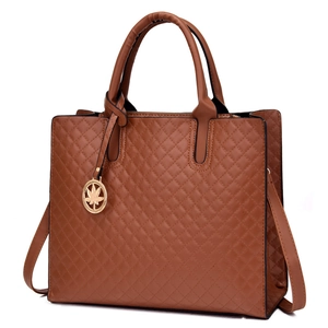 Brown quilted tote bag with maple leaf charm and adjustable shoulder strap on white backdrop
