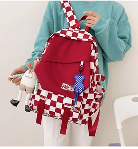 Detail of red checkerboard backpack featuring FASHION label and plush rabbit charm