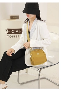 Modella che indossa una borsa a tracolla giallo zenzero in tessuto Oxford in un caffè