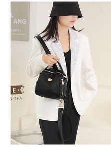 Modella asiatica mostra una borsa versatile in tessuto Oxford nero con dettagli dorati