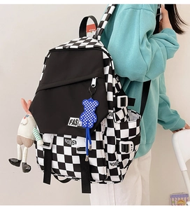Detail of checkered backpack featuring blue bear charm and cute rabbit plush toy pendant