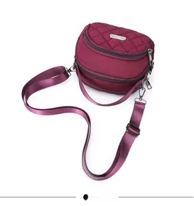 Dettaglio borsa a tracolla in nylon trapuntato bordeaux con tre scomparti con zip
