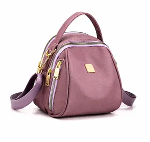 Dettaglio borsa viola in nylon con tasche a cerniera e finiture in metallo dorato