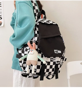 Detail of checkered backpack featuring fashion patch and cute plush bunny charm accessory