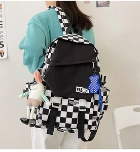 Detail of checkered backpack with Fashion patch, buckle straps and cute plush charms