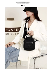 Close-up of black nylon crossbody bag featuring a circular logo and adjustable strap