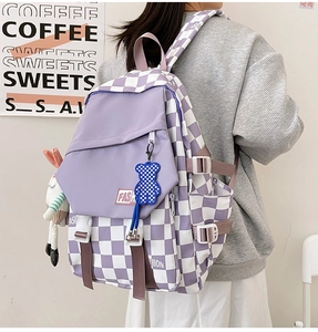 Detail of purple checkerboard backpack with cute plush charms and side buckle straps