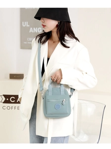 Detailed view of light blue nylon crossbody bag with wide strap in casual cafe setting
