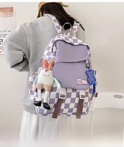 Detail of checkered backpack with purple flap pocket and cute hanging plush charms