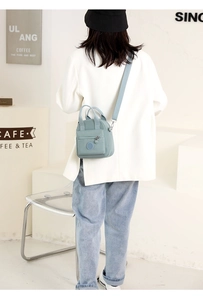 Rear view of a light blue nylon mini crossbody bag worn by a model in a cafe setting