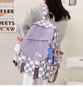 Detail of purple checkerboard backpack with fashion label and cute plush toy charms