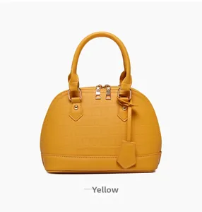 Detail view of yellow shell-shaped handbag with crocodile texture and gold hardware