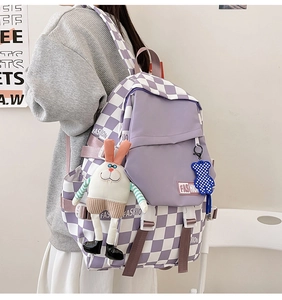 Detail of purple checkerboard backpack with fashion label and cute plush accessories
