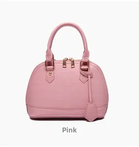 Detailed close-up of pink shell handbag featuring crocodile texture and gold hardware